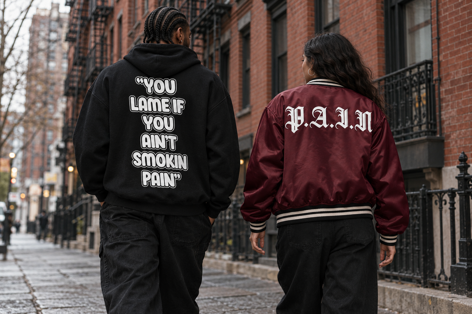 Lookbook showing the slogan on a black P.A.I.N hoodie and the wordmark across a burgundy satin jacket